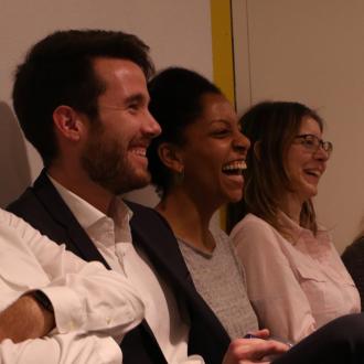 Un homme et deux femmes regardent sur la droite en rigolant